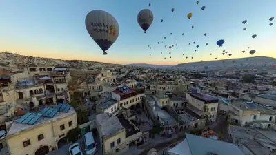 a group of hot air balloons flying over a city at Zenith Göreme in Istanbul