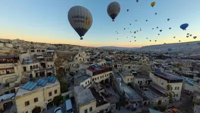 a group of hot air balloons flying over a city at Zenith Göreme in Istanbul