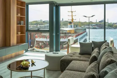 a living room with a couch and a boat in the water at DeCamondo Residence Karaköy in Istanbul