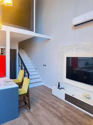a living room with a large tv and a staircase at Loft Sabırlı in Kaynarca