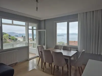 a dining room with a table and chairs and windows at Bosphorus view apartment Sarıyer in Sarıyer