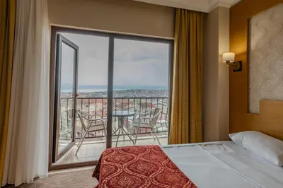 a bedroom with a bed and a balcony with a table and chairs at Mekanhan Hotel in Gebze