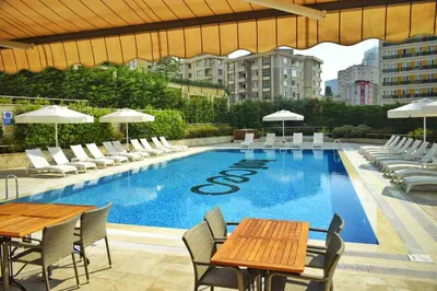 a swimming pool with tables and chairs and a building at Bof Hotels Ceo Suites Atasehir in Istanbul