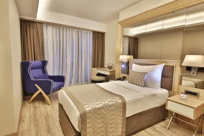 a hotel room with a bed and a blue chair at Bof Hotels Ceo Suites Atasehir in Istanbul