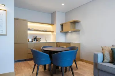a kitchen and dining room with a table and blue chairs at Marriott Executive Apartments Istanbul Investvadi in Istanbul