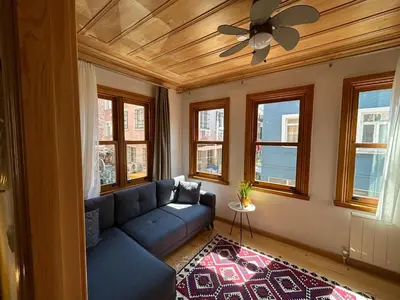 a living room with a blue couch and windows at Balat Rose - Charming Wooden House with Terrace in Istanbul