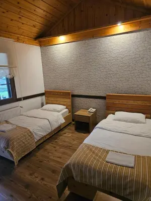 two beds in a room with wooden floors at Değirmenbaşı Otel & Restoran in Ümmiye