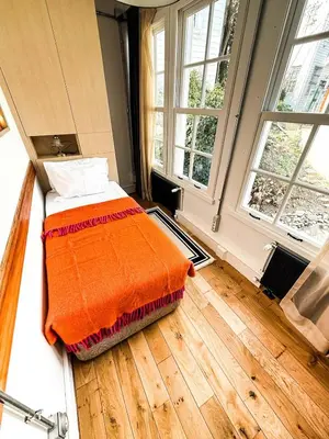 a bed with an orange blanket in a room with windows at Sel Maison in Istanbul