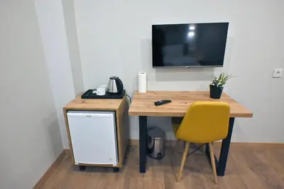 a desk with a yellow chair and a television on a wall at The Han YK Hotel in Avcılar