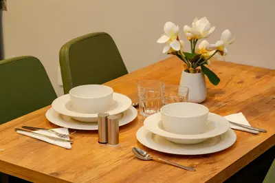 a wooden table with white dishes and a vase of flowers at The Han YK Hotel in Avcılar