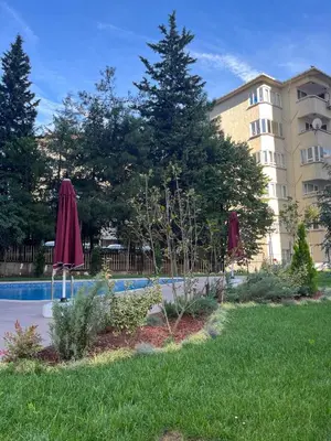 a pool with umbrellas in the grass next to a building at Köylüm Bostanci Residence-3 in Istanbul