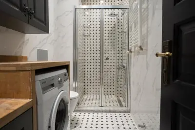 a bathroom with a shower and a washing machine at Cozy Urban 1BR Nest with Balcony Charm in Istanbul