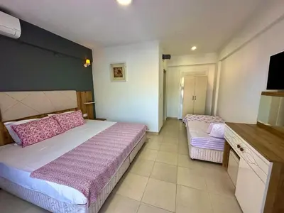 a bedroom with a large bed with pink sheets at ADASU Otel in Marmara
