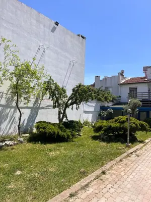 a building with trees and bushes next to a sidewalk at Ennis İnn Resort Hotel in Marmaraereglisi