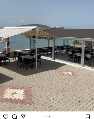a patio with tables and chairs and a view of the ocean at Kum Motel in Marmara