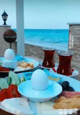 a table with plates of food and a view of the ocean at Kum Motel in Marmara