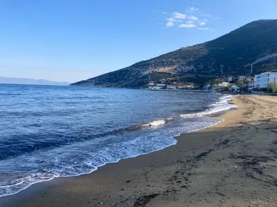 a beach with the ocean and buildings in the background at Kalemi Pansiyon in Marmara