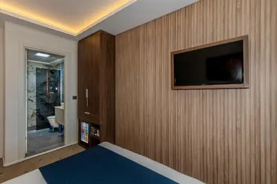 a bedroom with a tv on a wooden wall at Airport Waves Hotel in Arnavutköy