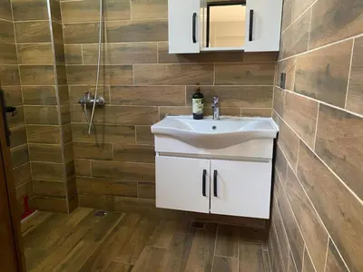 a bathroom with a white sink and wooden floors at Kocaeli Başiskele Doğayla İç İçe Özel Havuzlu Tatil Evi in Bahçecik