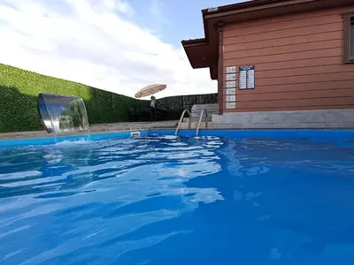 a swimming pool with two chairs in front of a house at Kandıra villam in Duraklı