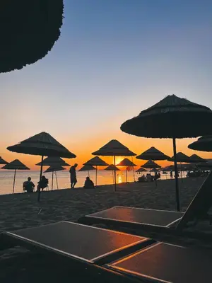 a group of people sitting under umbrellas on a beach at Yağcı Hotel Erdek in Erdek
