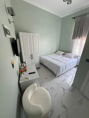 a white bedroom with a chair and a bed at Meydan 76 in Adalar