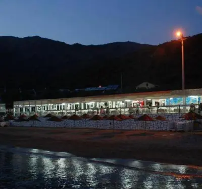 a building on a beach at night with the lights on at boncuk motel in Marmara