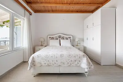 a white bedroom with a bed and a window at Marmara Yali Evi in Marmara