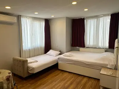 two beds in a room with two windows at Kaman Home Apart in Istanbul