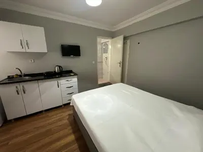 a bedroom with a white bed and a kitchen at Kaman Home Apart in Istanbul