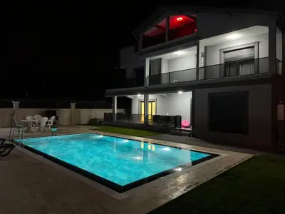 a swimming pool in front of a house at night at Lux Villa Silivri Kavakli in Silivri