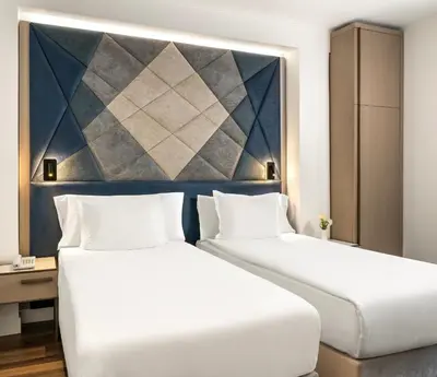 two beds in a hotel room with a painting on the wall at Adamar Hotel-Special Category in Istanbul