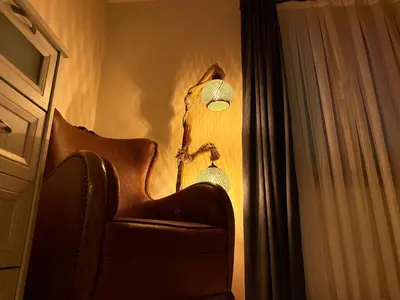 a chair with a lamp next to a curtain at Manzara Ödüllü Büyük Havuzlu Premium Villa in Dibektaş