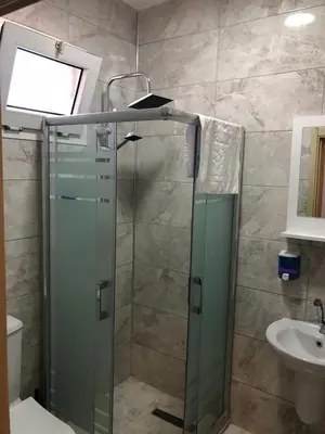 a bathroom with a glass shower and a sink at GOLD SARAY PANSİYOn in Saray