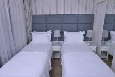 two beds in a room with two tables and two lamps at T & R İstanbul hotel in Istanbul