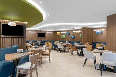 a dining room with tables and chairs and a flat screen tv at Hampton By Hilton Istanbul Sisli in Istanbul