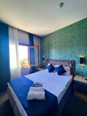 a bedroom with a large bed with blue walls at GÜNEŞLİ SUİT OTEl in Istanbul