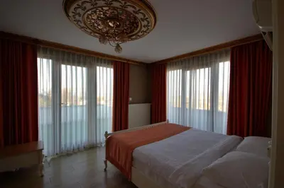a bedroom with a bed with red curtains and a chandelier at My Green Otel in Sapanca