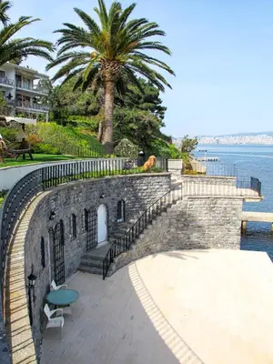 a brick wall with a table and a chair next to the water at Villa Büyükada I Private Pier & Seawater Pool in Istanbul