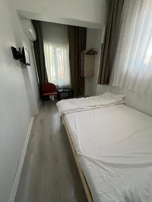 a small room with two beds and a red chair at Şişli Suites - Room32 in Istanbul