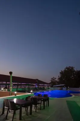 a group of tables and chairs next to a pool at night at CANPOLAT Sapanca Hotel in Sapanca