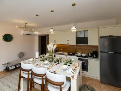 a kitchen with a table with white chairs and a black refrigerator at sevim suites Nişantaşı Rumeli in Istanbul