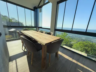 a wooden table and chairs in a room with windows at Adesa View Villas in Sapanca