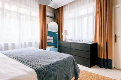 a bedroom with a bed and a dresser and windows at Stylish Flat w Balcony – 5 Mins from Taksim Square in Istanbul