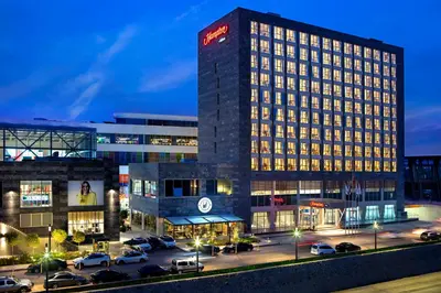 a building with a lot of cars parked in a parking lot at Hampton By Hilton Kocaeli Symbol in Kocaeli