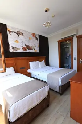 a hotel room with two beds and a painting on the wall at New House Hotel in Istanbul