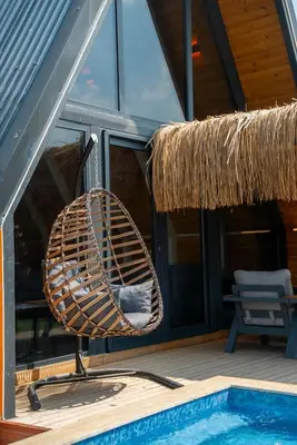 a rattan chair sitting next to a swimming pool at Armoni Life Bungalov in Yanık