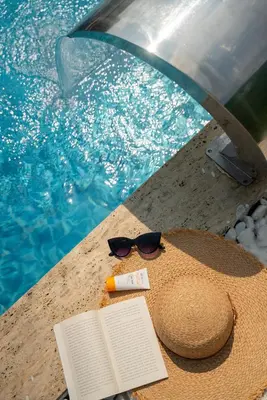 a hat and sunglasses and a book next to a swimming pool at Armoni Life Bungalov in Yanık
