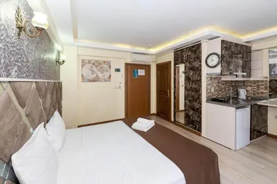 a bedroom with a white bed and a kitchen at Terra Suites in Istanbul