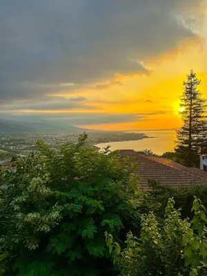 a sunset over the ocean with trees in the foreground at Cozy 4BR Villa with Lake View and Comfort Galore in Sapanca